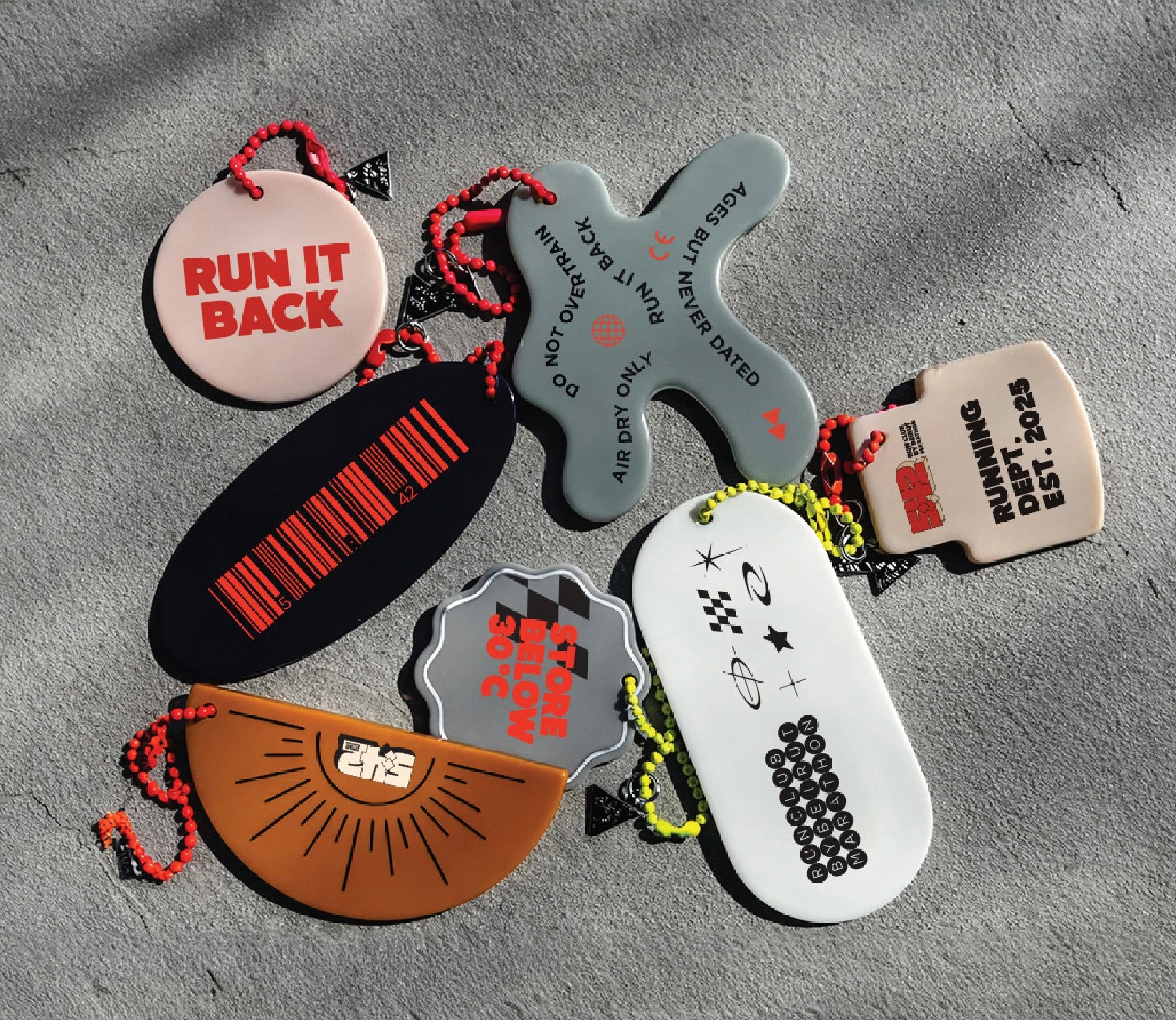 Collection of 5:42 Run Club keyrings and tags in red, orange, black and silver