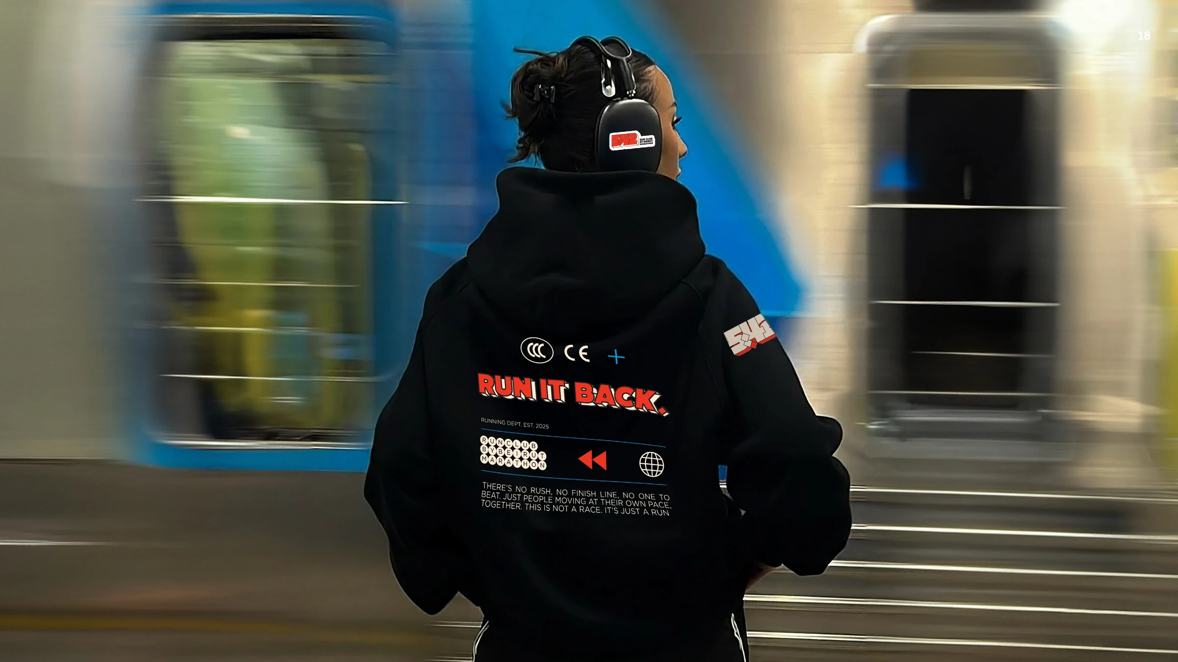 Runner wearing a black 5:42 hoodie beside a passing train
