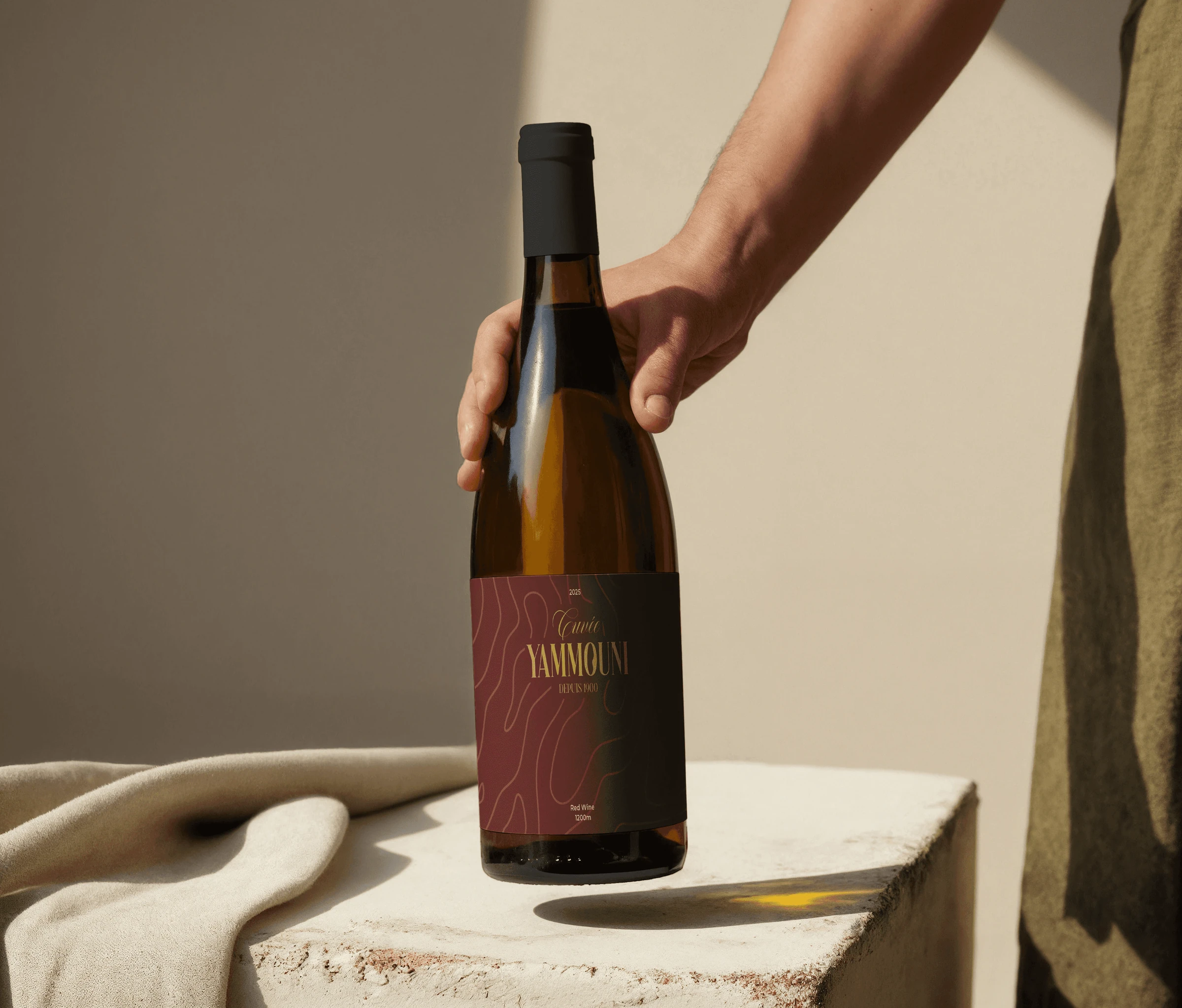 Hand placing a Cuvée Yammouni wine bottle on a sunlit table