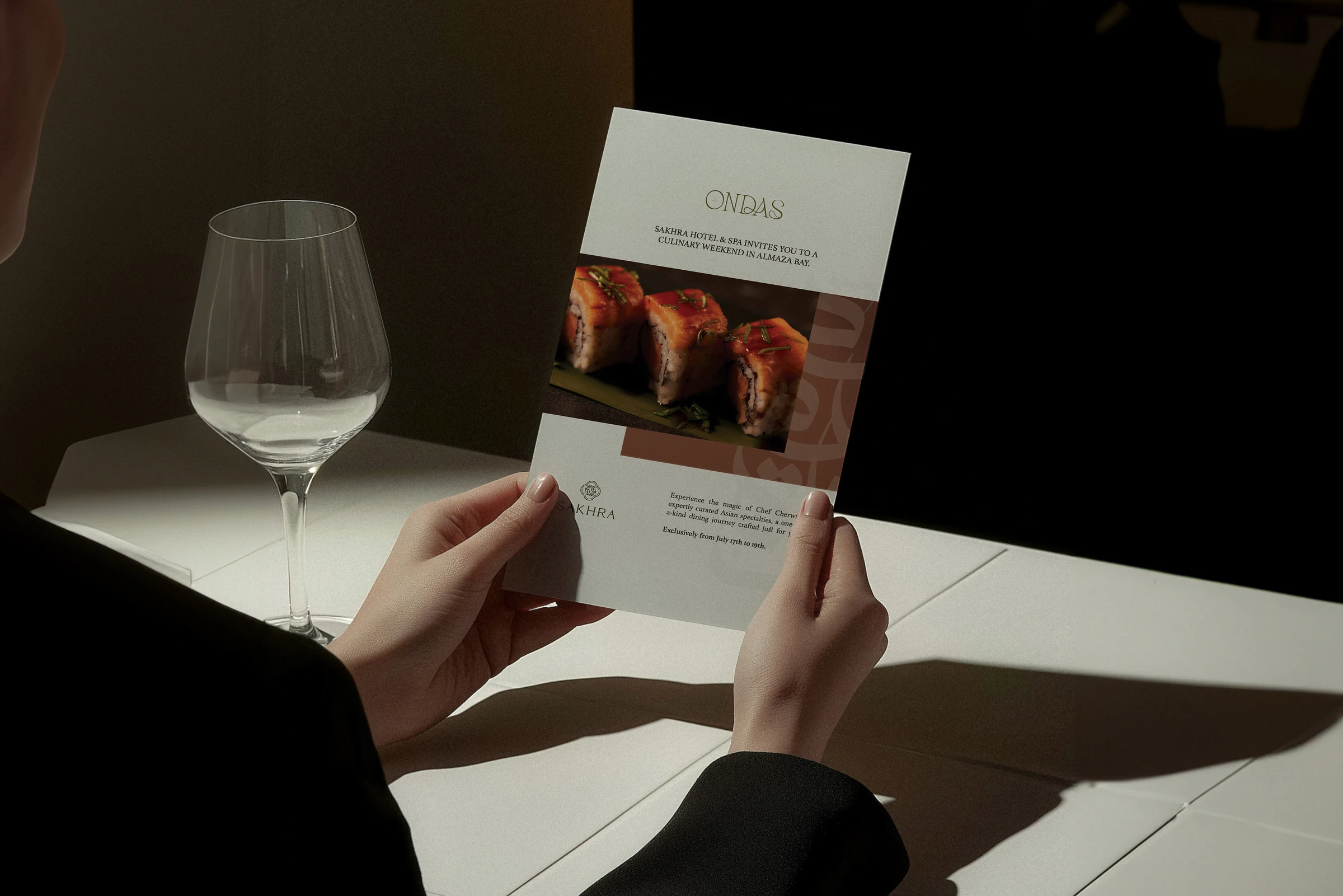 Restaurant menu held beside a wine glass on a table