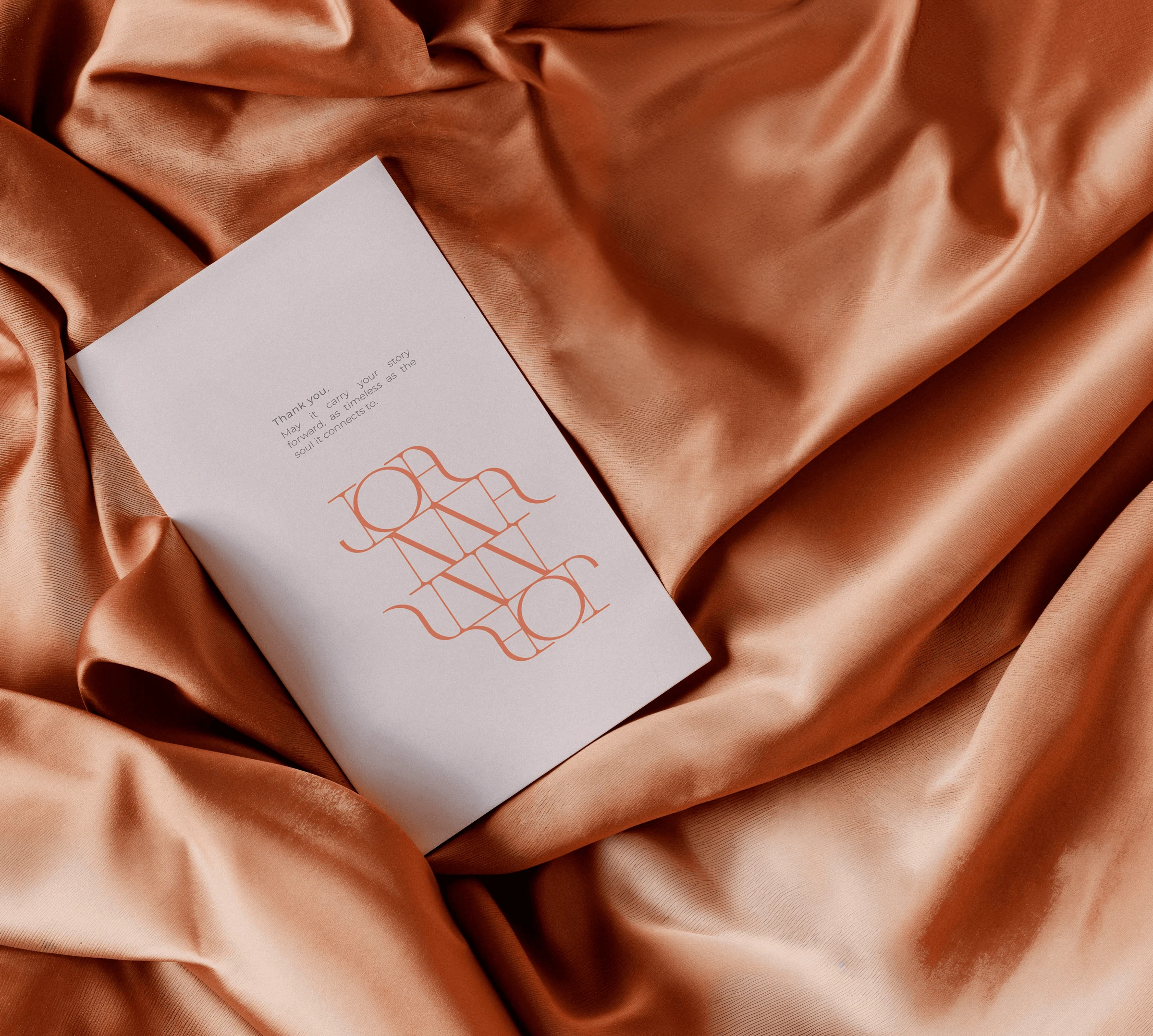 Joanna Achkar brand card with a line-drawn monogram on copper-colored fabric