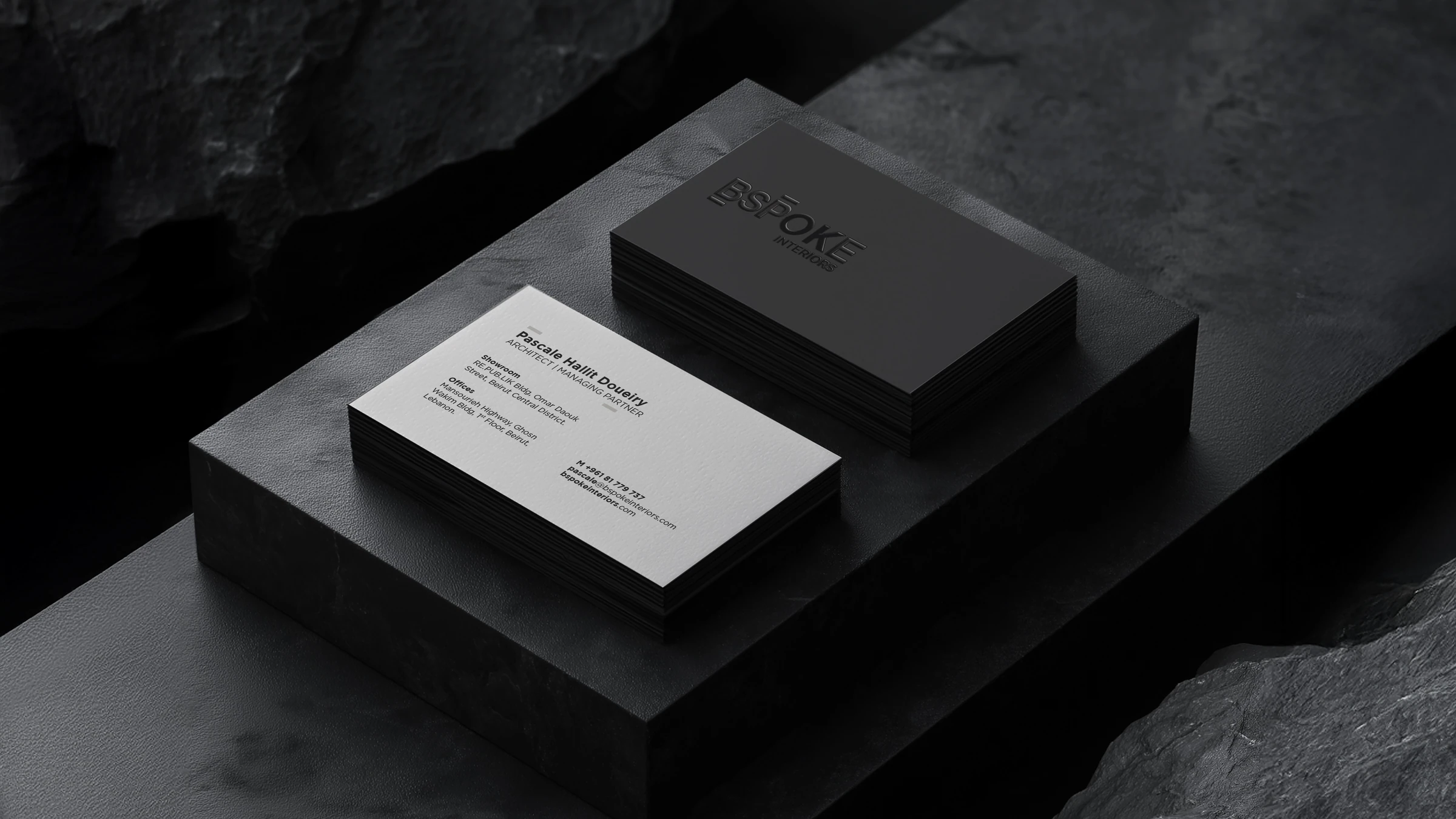 Black and white Bspoke Interiors business cards on a dark stone surface